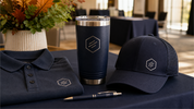 Promotional products for fall trade shows — engraved tumbler, leather patch hat, and branded apparel on a trade show booth table